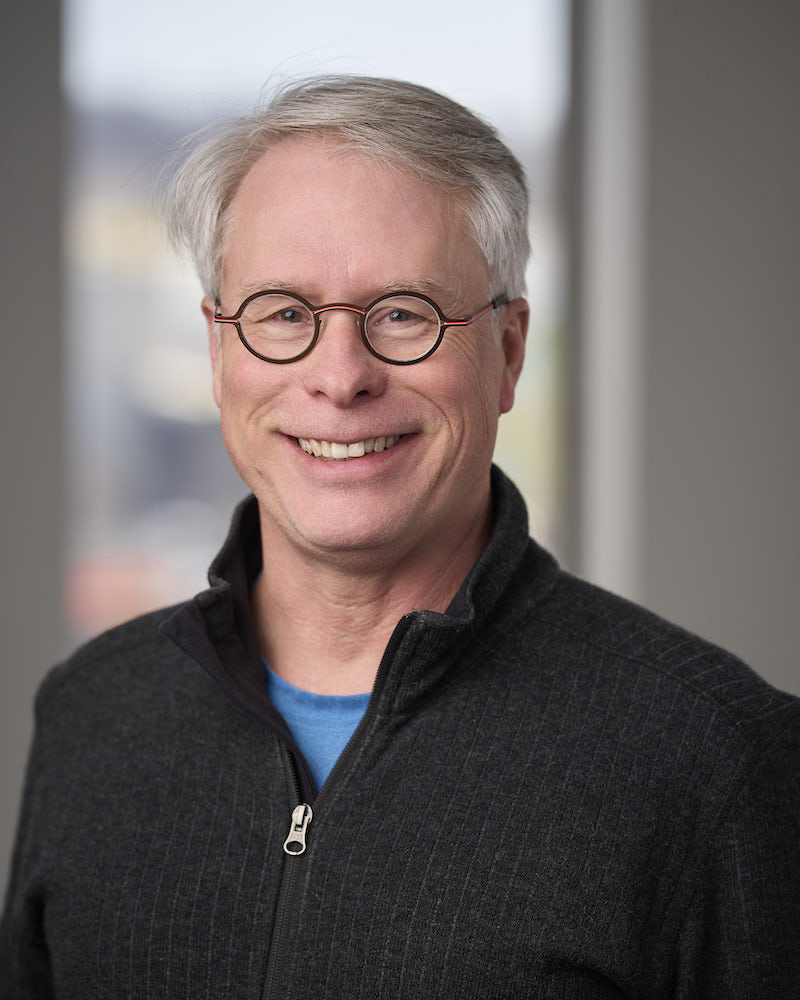 headshot of older white man in zip hoodie
