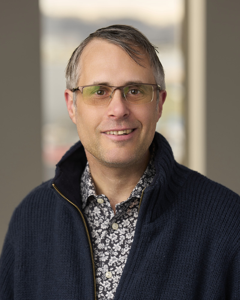 headshot of older white man in zip hoodie