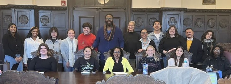 group of people posing and smiling after meeting with colloquium speaker
