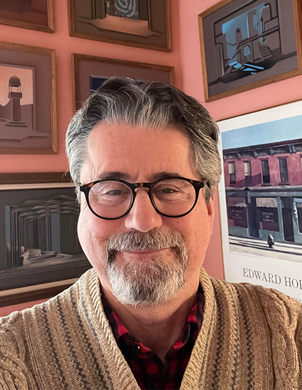 Thomas Leff with many framed artistic photographs behind him.