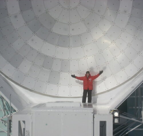 small figure in front of a parabolic dish