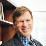 professor wers dark suit with blue shirt and gray tie