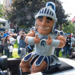 Mascot of a Spartan warrior gives the thumbs up in a parade car