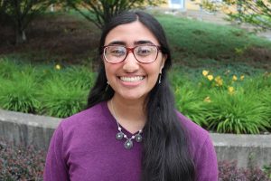 Student with long black hair and glasses smiles
