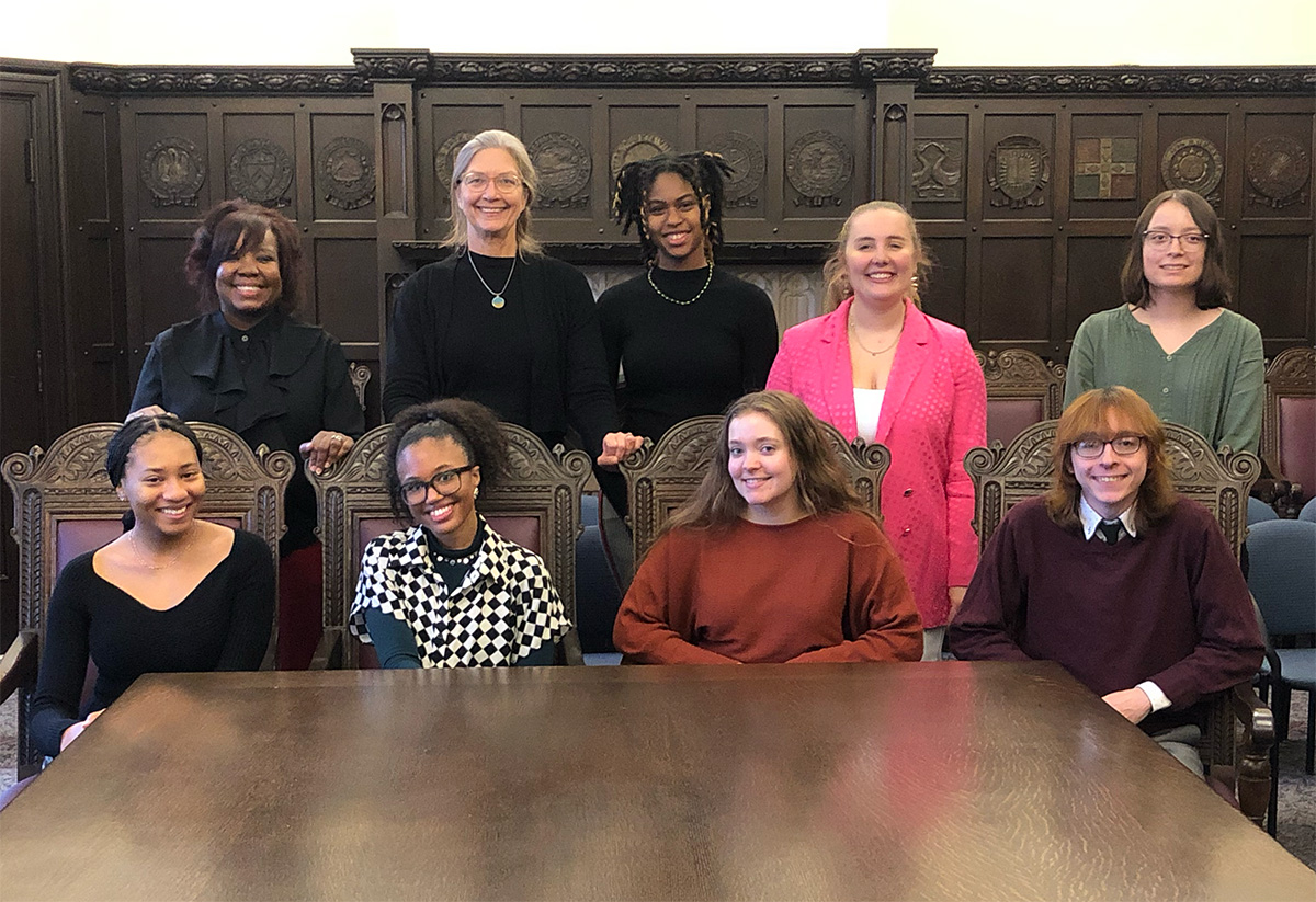 The 8 CWRU sociology students seated at a table with advisor Mary Erdmans following the students' capstone research project presentations in December 2022